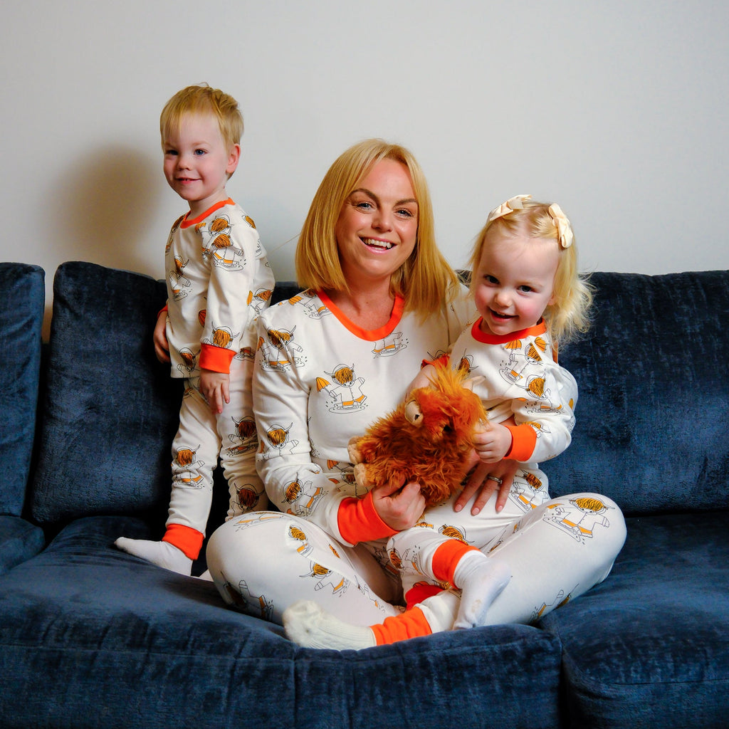 Woman and two children in matching pajamas sitting on a blue couch.